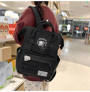 Model wearing a black school backpack featuring cute toast embroidery and letter detail