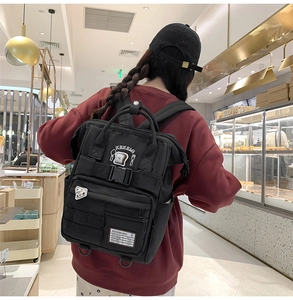 Detail view of black canvas backpack with cute embroidery and multiple utility pockets