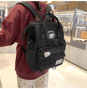 Close-up of black canvas backpack with cartoon toast patch and buckle details on straps
