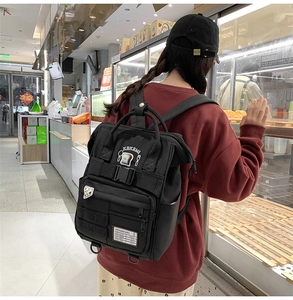 Detail of black waterproof nylon backpack with multiple zippers and decorative straps