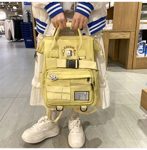 Detail of a creamy yellow canvas backpack with KEKEMI embroidery and black buckles