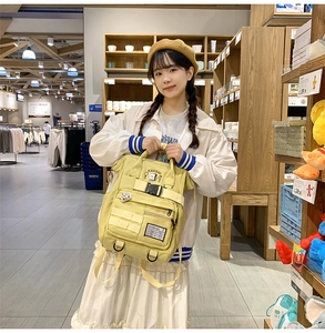 Detail of yellow canvas backpack featuring multi-pocket design and adjustable buckles