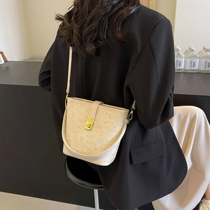 Chic cream bucket bag with graffiti prints worn by model in a minimalist setting
