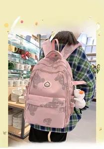 Pink printed backpack with bear patterns and a white duck plush charm shown in use