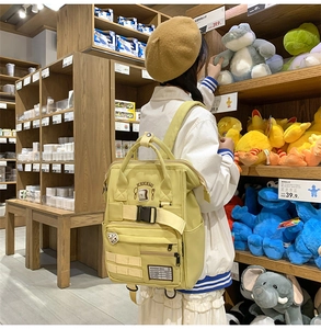 Detail of light green functional backpack featuring buckle straps and cute embroidery