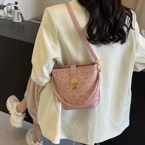 Pink bucket bag with graffiti prints and gold lock worn with a white blazer