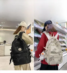 Detailed side and back views of floral print backpacks with duck charms in black and cream