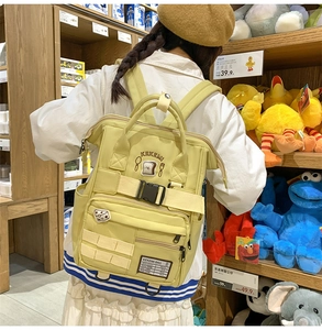 Detail view of solid yellow backpack with multiple pockets and cute embroidery