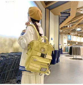 Side view of a large yellow canvas backpack with decorative patches and buckles on a model