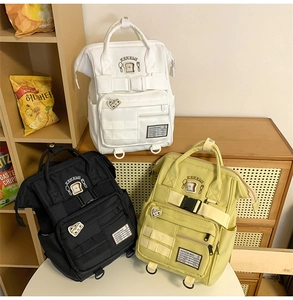 Detail of multi-pocket backpacks in white black and yellow with embroidery patches