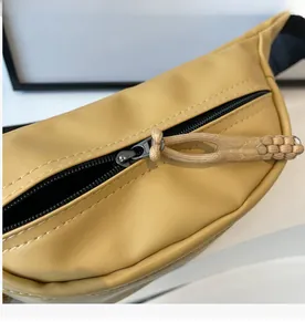 Detail eines schwarzen Reißverschlusses mit Kordelzug an einer gelben Leder-Brusttasche