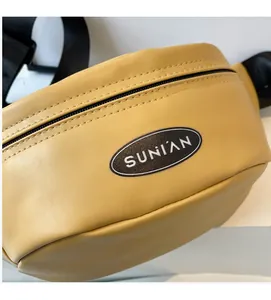 Detailansicht der gelben Brusttasche aus genarbtem Leder mit SUNIAN-Logo und Reißverschluss