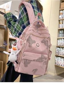 Pink printed backpack with bear patterns and duck pendant shown from a side view