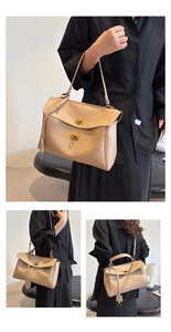 Detail of beige leather handbag featuring a golden turn-lock closure and sleek metal hardware