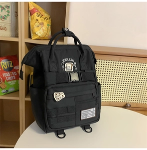 Detail of black canvas backpack showing cute bread patches and multi-pocket design