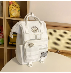 Detailed view of white multi-pocket backpack with cute toast patches and embroidery