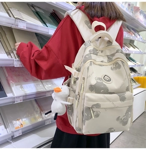 Cream canvas backpack with koala print and plush duck charm in a library setting