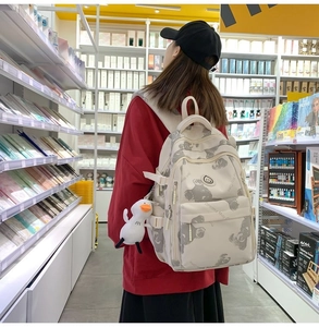 Detail view of cream nylon backpack with bear print and cute plush duck charm