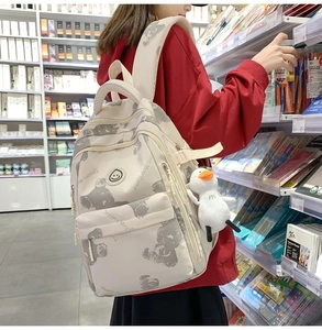 Detail of floral bear print backpack with plush duck charm and smile logo on the side