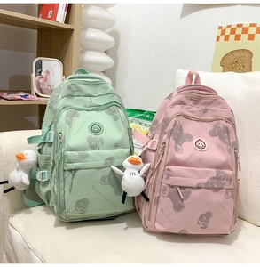 Detail of multi-pocket canvas backpacks in mint and pink with cute duck charms