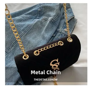 Détail du sac bandoulière en velours noir avec chaîne dorée et gland sur denim
