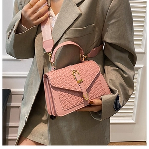 Detail view of pink woven texture crossbody bag with gold buckle and wide strap on model