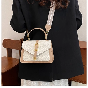 Detail of color-block woven shoulder bag with wide geometric pattern strap on model