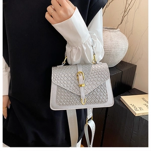 Detail view of grey woven texture flap bag with gold buckle and wide canvas strap