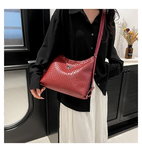 Gros plan du sac à bandoulière rouge tressé avec logo nœud argenté sur modèle
