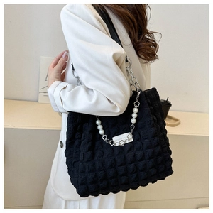 Detail of black bubble texture fabric bag with pearl and metal chain shoulder strap