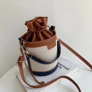 Détail du sac seau bicolore montrant la texture en toile et le cordon de serrage en cuir