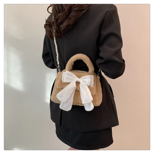 Detalle de bolso bandolera de felpa con lazo blanco y elegante cadena de perlas