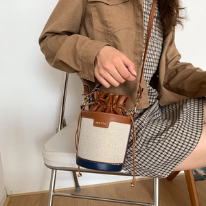 Détail du sac seau en toile avec garniture en cuir et cordon de serrage sur modèle