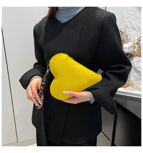 Detail view of heart-shaped yellow leather handbag with colorful Love printed wristlet