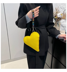Detail of yellow heart leather pouch with colorful LOVE ribbon handle on black coat