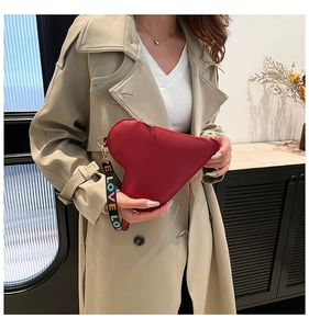 Close-up of red heart-shaped leather bag with colorful LOVE lettered woven strap handle