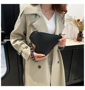 Detail of heart-shaped black leather pouch with gold zipper and LOVE wristlet strap