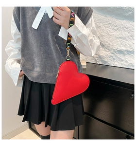 Detail of red heart-shaped leather purse with gold zipper and LOVE print wrist strap