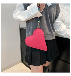 Close-up of heart-shaped crossbody bag with pink lychee leather and LOVE rainbow strap