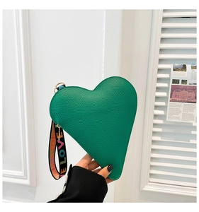 Detail of green heart-shaped pouch with lychee leather texture and LOVE wrist strap