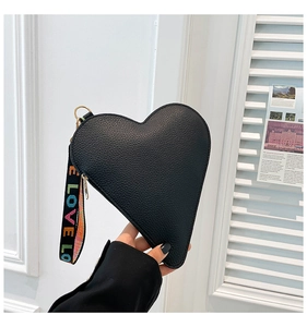 Close-up of black heart-shaped handbag featuring litchi texture and a colorful LOVE strap