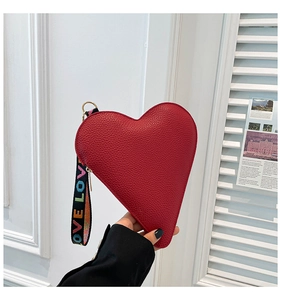 Detail of red heart-shaped clutch bag with LOVE printed ribbon handle and pebble texture