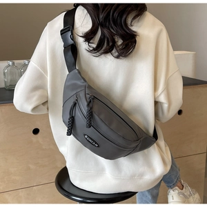 Detail der dunkelgrauen Nylon-Brusttasche mit gewebten Abziehern und Markenlogo