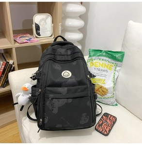 Detail of black printed backpack with bear pattern and cute duck plush keychain accessory