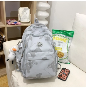 Detail view of grey printed backpack featuring multi-pockets and a cute duck keychain