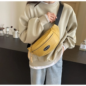 Detail der gelben minimalistischen Crossbody-Brusttasche mit schwarzem Schultergurt