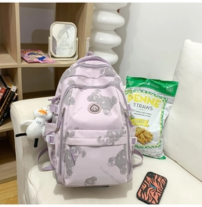 Detail view of purple printed backpack with bear patterns and cute white duck pendant