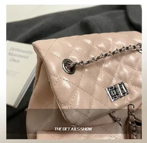 Close-up of silver metal twist lock and chain detail on quilted leather backpack