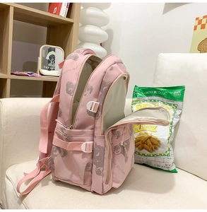 Detail of pink backpack with bear prints and Dreams May Come text on white sofa