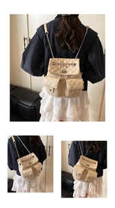 Detail of beige quilted leather backpack featuring diamond stitching and metal chain straps